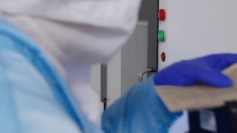 clip-3976073905-gloved-technician-cleanroom-attire-operates-pass-through-chamber