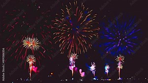 A series of fireworks are lit up in the sky, with each firework having a different color. The fireworks are arranged in a row, with the first firework being blue, the second being red