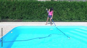 Cleaning the home pool. The woman sucks and cleans the swimming pool. Seasonal work from an aerial perspective.