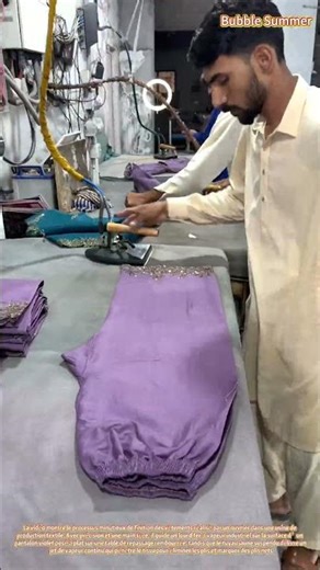 Finition des vêtements : repassage de pantalons à l'aide d'un fer à vapeur industriel