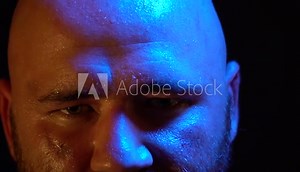 Bald Roman gladiator with a beard and scar in his face puts off a helmet from his head and looks in camera