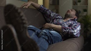 Drunken man sleeping on couch, scratching belly in his sleep, after night out