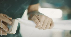 Surfboard shaper sanding the nose of a surfboard, skilled craftsman shaping a surfboard with focus and precision