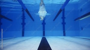 Muscular man under water in a swimming pool in super slow motion
