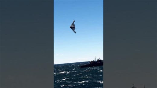 IRAN: A B-2 Spirit stealth bomber flies by a US Carrier in the Persian Gulf to raise troop morale. | James M. Janzen