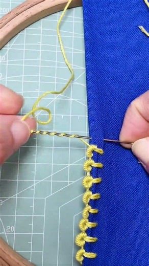 embroidering beautiful yellow patterns with needle and thread on blue fabric for home decorations