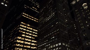 New York City Financial District skyscrapers near Wall Street and the New York Stock Exchange ("NYSE"). Nighttime. Office lights are on.