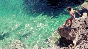 clip-1013306792-brave-girl-jumping-cliff-transparent-blue-sea