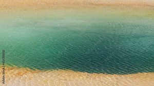 Clear transparent rippling water surface texture in vivid green blue deep volcano geyser basin. Volcanic water flowing in pool. Sunlight reflecting on water background. 4K Yellowstone National park