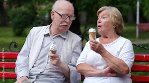 Grandpa and grandma are sitting on a bench in a park in New York, USA