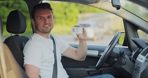 Male smiling and holding digital driving license. Man successfully passed driving school test. Man with driving license. Driver courses, exam and people concept.