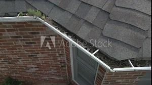 Dirty, metal gutters on a residential home are clogged with leaves and debris.