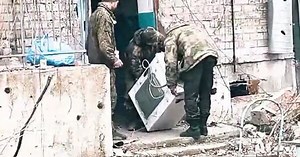 Three occupiers carrying washing machine along street of occupied and destroyed Avdiivka. VIDEO