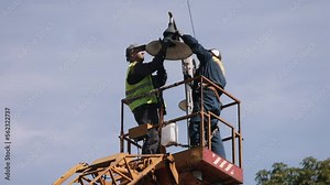 during installation, worker repair, metal pole. Worker is fixing street light pole lamp at height, replacing led lights. Men fixing lamp pole lamp, fixing street light