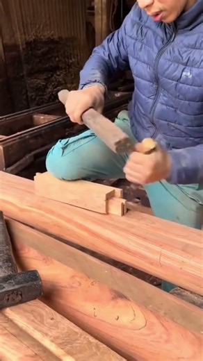 hammering a sharp metal chisel into a wooden beam to create precise joints for a large structure