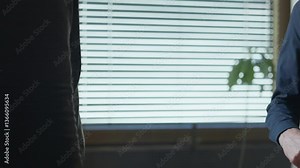 Two businessmen in secret deal passing top secret folder with classified information inside office. Undercover agent or criminal exchange. Shaking hands after transaction. Exposing government files