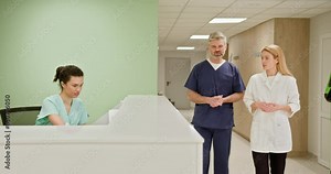 Group of medical staff at a hospital reception desk collaborating and reviewing patient records. Healthcare professionals in a clinical setting. Medical Staff Working At Hospital Reception Desk.