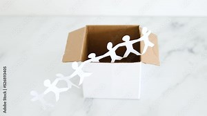 Think outside the box concept with paper people chain getting out of a white box on white marble