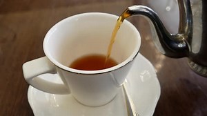 Pouring tea from old silver teapot