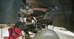Mechanic working on the partially disassembled engine of a modern electric vehicle, focusing on maintenance and repair in a workshop. EV repair concept. Auto Service, Electric Car Battery Handling.