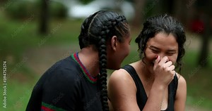 Two diverse friends laughing and smiling together. Mixed race girlfriends talking in conversation outside. Authentic real life laugh and smile