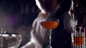 The bartender is preparing a cocktail "Rob Roy". Sprinkles smoky scotch whisky on a cocktail glass. Maybe it's an Old Pal cocktail. Slow motion.