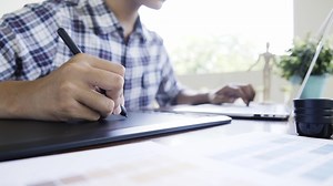 Download Close up male hand using graphics tablet on table.  for free