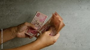Hands holding ten turkish lira notes against a concrete background showcasing turkish currency