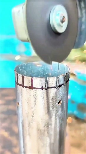 Sparks fly as cutting disc scores pipe—vertical slits trace black-marked steel edge