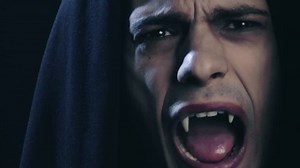 Male vampire coming out from darkness in pain showing fangs