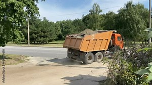 articulated heavy industrial yellow dumper trucks driving on new highway road construction site on sunny day. Construction equipment machinery working on open pit