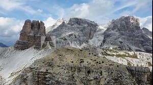 Awesome 4K footage of a young hiker standing on a mountain top surrounded by the amazing landscape and the huge rock formations of the Dolomites in North Italy on a clear blue day.