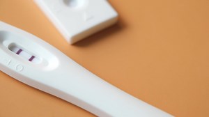 Pregnancy test kit with positive result on color background