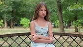 Frightened, upset girl sitting on a park bench. Depression,...