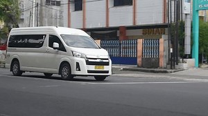 Surakarta, Central Java, Indonesia-Nov 3, 2024: a white Toyota Hiace Premio tour van passing the main street of Surakarta