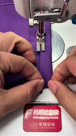 sewing a bright purple fabric precisely using an electric industrial sewing machine in workshop