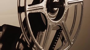 Download Close up of 8mm movie projector, showing half film reel unrolling film in 4K for free