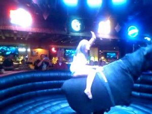 Girl with skirt riding electronic bull in Vegas.