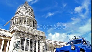 HAVANA, CUBA - OCTOBER 8, 2014: Old classic American cars on the streets of Havana city, Cuba.Capital building in the background.Urban scene, people and traffic.Slow motion, high speed camera
