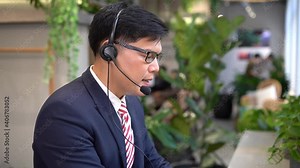 Young call center operator taking a call at the help desk. Smiling customer support operator at work. Businessman using a headset for hands free communication.