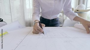 4K resolution, Selective focus hand with a pen writing on blueprint on the desk in office Engineer or Architect workplace. Architect working in office.