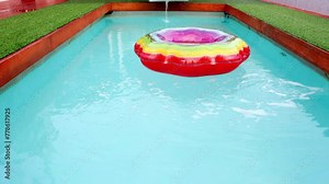 An abandoned inflatable ring floats in an empty swimming pool