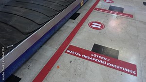 Antalya Airport, Antalya, Turkey - 16th of July 2020: 4K Covid-19 travelling safety - Moving baggage carousel and social distance marking on the airport floor