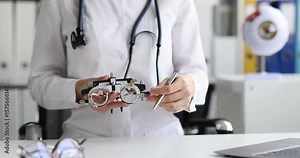 Woman doctor explains phoropter work at appointment in hospital. Female ophthalmologist prepares to checkup patient eyesight in medical office