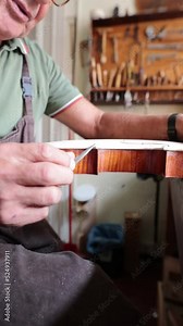 luthier carving the shape of the outside of the front of a violin with gouge