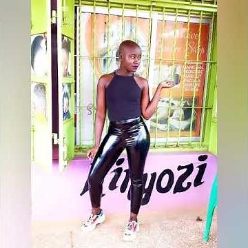 Bald woman in latex and leather leggings.