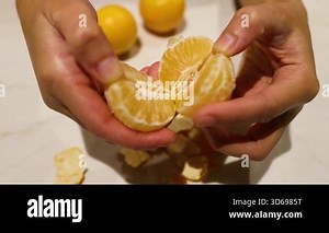 Hands peeling and splitting an orange