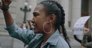 Angry activists marching and protesting in the city. Woman protesting with a group of people on the road.