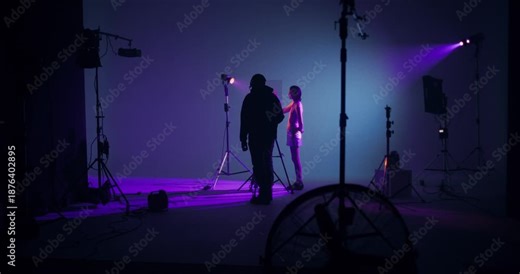 The photographer takes off the model's hand behind the glass. Working as a photographer and model in a studio