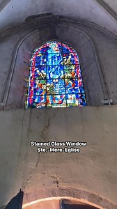 This stained glass window depicts planes and paratroopers dropping into the city of Sainte-Mère-Église #glass #window #city #walk #like | D-Day History